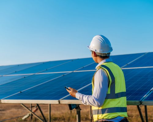 joven-tecnico-asiatico-parado-hablando-telefono-inteligente-largas-filas-paneles-solares-fotovoltaicos-copiando-espacio-scaled.jpg